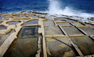 Wave crashing against saltpans on the coast of Malta clipart