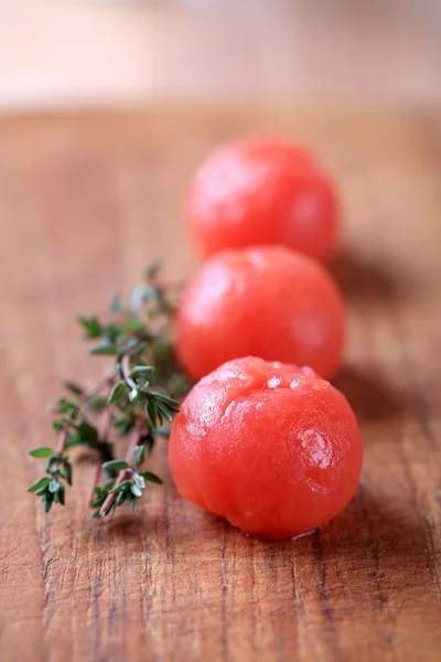 stock image Peeled cherry tomatoes and a sprig of fresh thyme