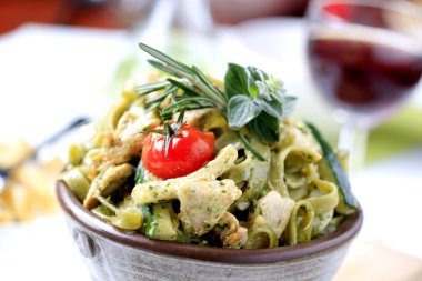 Spinach fettuccine with chicken, basil pesto and cream clipart