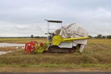 A rice harvester parked by the roadside near pottuvil in sri lanka with flooded fields and cloudy skies clipart