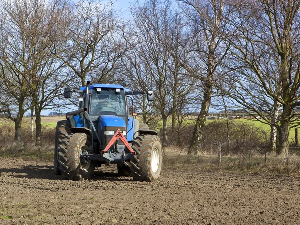 Blue tractor cultivating — Stok fotoğraf