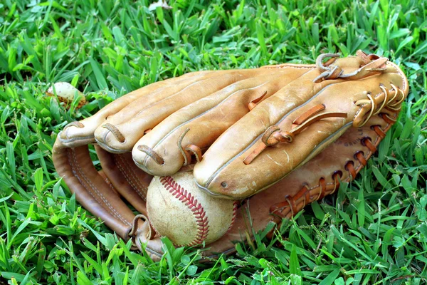 Honkbal handschoen en bal leggen in gras — Stockfoto