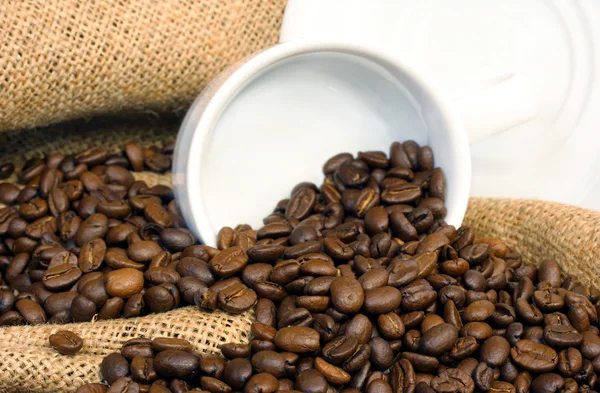 Coffee beans, burlap and a white cup — Stock Photo, Image