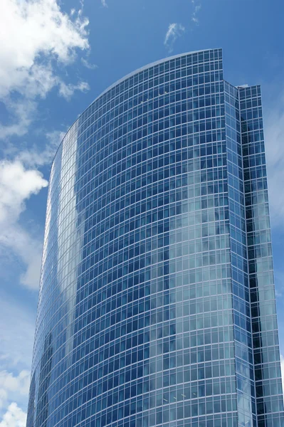 Отражение облачного неба в стеклянной стене офисного здания — стоковое фото