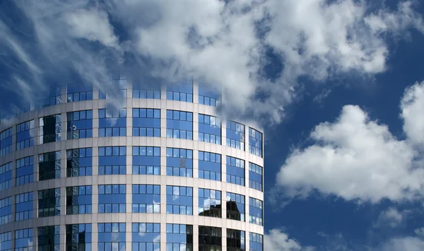 Reflejo de un cielo nublado en la pared de cristal de un edificio de oficinas — Foto de Stock