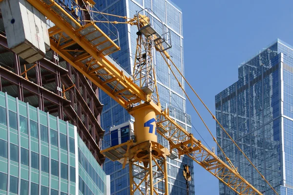 Construction crane at the windows of a skyscraper backdrop of glass and con — Stock Photo, Image