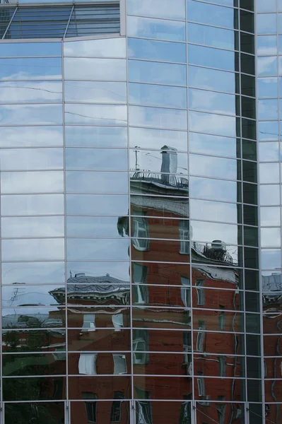 Reflectie van wolken, blauwe hemel en de andere gebouwen in de glazen ramen — Stockfoto