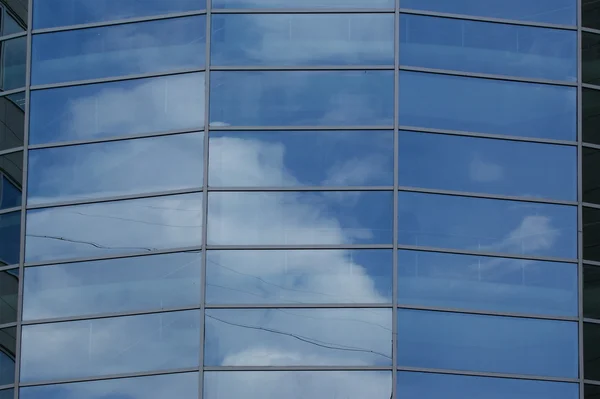 Reflexão de um céu nublado na parede de vidro de um edifício de escritório — Fotografia de Stock