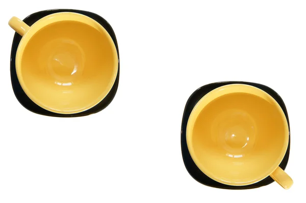 Large yellow cup and black saucer, top view, isolated on white — Stock Photo, Image
