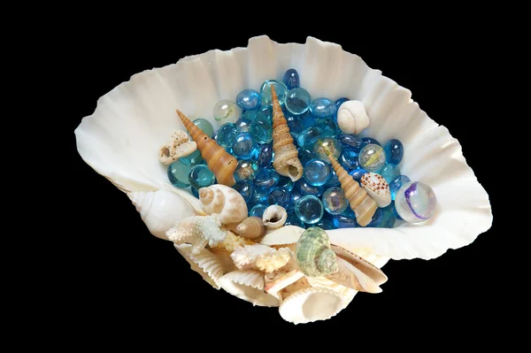 Большая морская раковина с голубыми стеклянными камнями и маленькими ракушками, изолированными на чёрном — стоковое фото