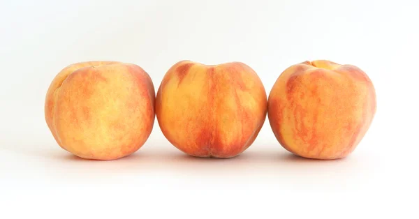 Три больших спелых персика на белом фоне — стоковое фото