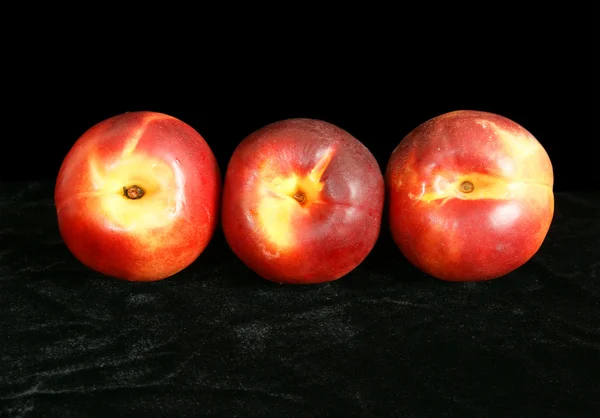 Três grandes nectarinas maduras, sobre um fundo preto — Fotografia de Stock