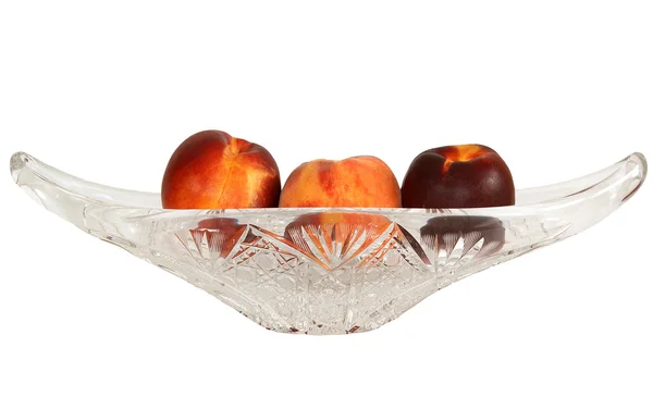 Big, ripe nectarines in a crystal vase for fruits, isolated on a white back — Stock Photo, Image