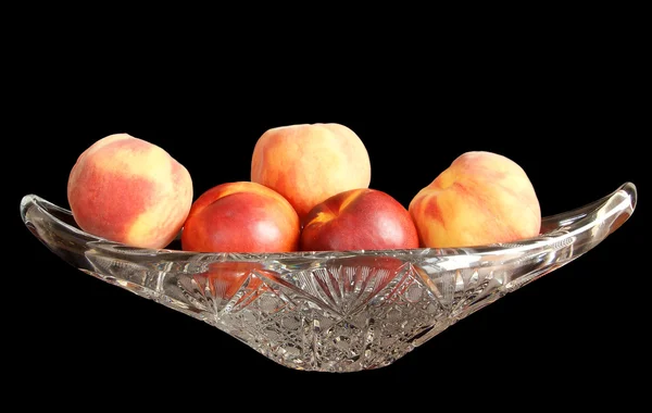 Grande, nectarinas maduras e pêssegos em um vaso de cristal para frutas, isolado em — Fotografia de Stock