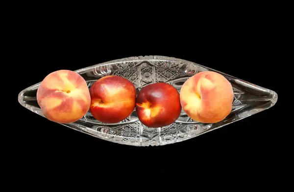 Великі, стиглі нектарини та персики у кришталевій вазі для фруктів, ізольовані на — стокове фото