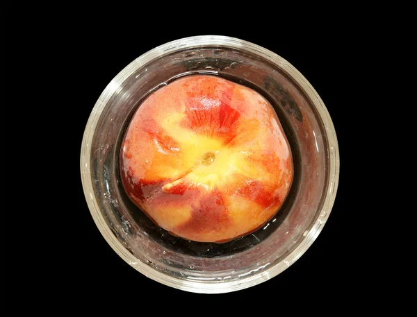 Большой спелый персик в стеклянной вазе, вид сверху, изолированный на черном фоне — стоковое фото