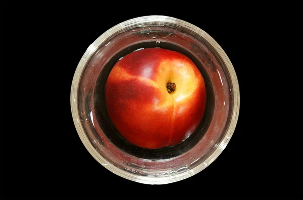 Gran nectarina madura en un jarrón de vidrio, vista superior, aislada sobre fondo negro — Foto de Stock