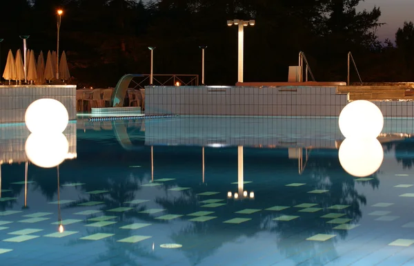 Gran luz brillante en forma de una bola en el agua por la noche en la piscina — Foto de Stock