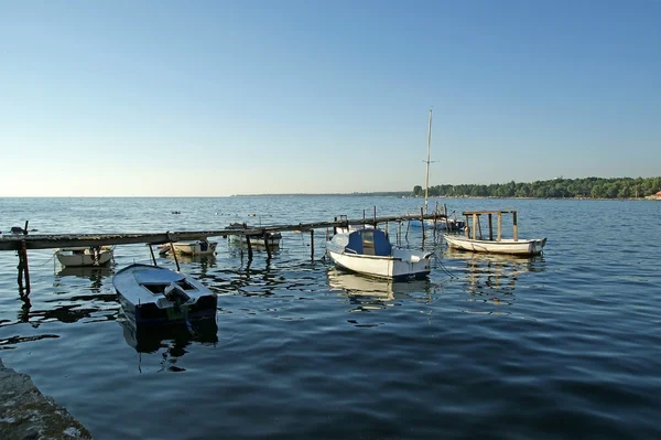 A fából készült móló, a hajó és jacht látható a háttérben, a tó vizének az — Stock Fotó