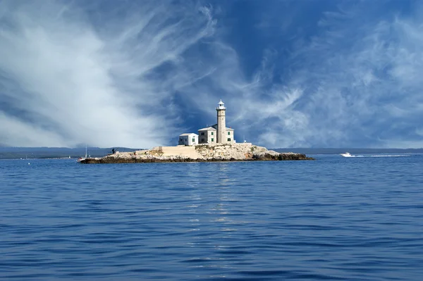 Маяк в море против голубого неба с облаками — стоковое фото