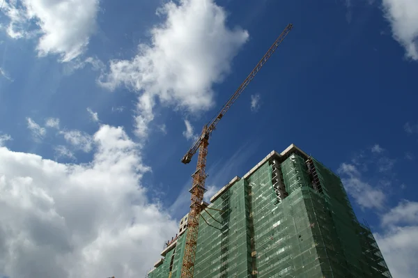 stock image Building crane at the background of a multi-storey building under construction