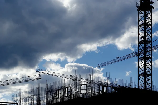 stock image Building crane at the background of a multi-storey building under construction