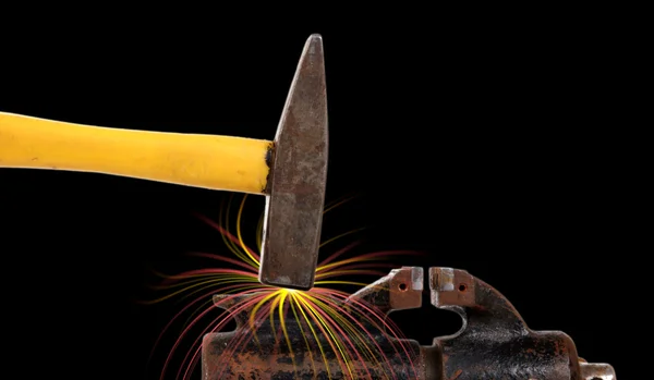Rusty old bench vise and a hammer with sparks from a blow on a black backgr — Stock Photo, Image