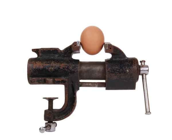 Egg trapped in the old rusty metalwork vice, on a white background — Stock Photo, Image