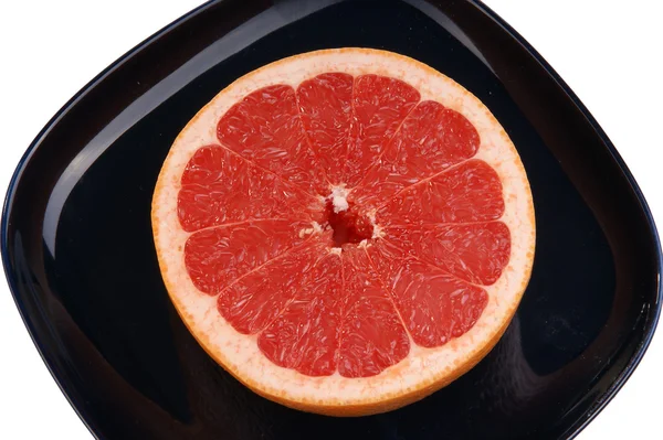 Pomelo rojo maduro. La fruta cortada en un plato azul oscuro — Foto de Stock