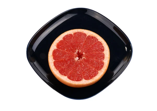 Спелый красный грейпфрут. Срезанные плоды на темно-синей тарелке — стоковое фото