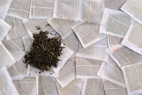Teabags with green tea pile — Stock Photo, Image