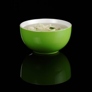 Chinese noodle soup in a green bowl photographed on black with a reflection clipart