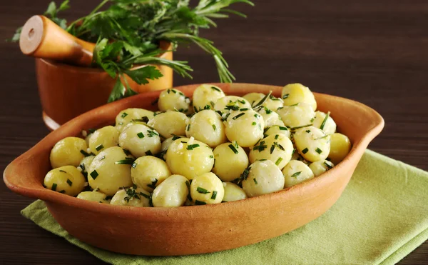 stock image Small potatoes with herbs, such as parsley, thyme and rosemary with a mortar filled with herbs in the background (Selective Focus)