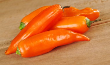 A bunch of ajis (Peruvian hot pepper which is used a lot in the Peruvian cuisine) on a wooden board (Selective Focus, Focus on the aji in the front) clipart