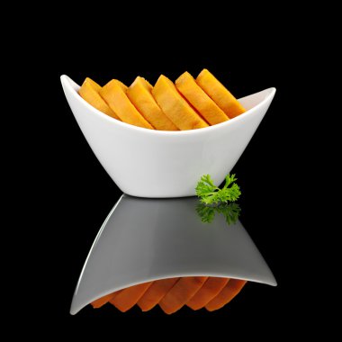 Cooked sweet potato slices (lat. Ipomoea batatas) in white bowl garnished with a parsley leaf and photographed on black (Selective Focus, Focus on the front) clipart