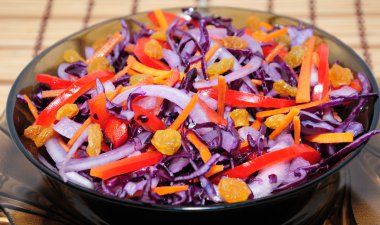 Salad of blue cabbage with carrots, peppers and raisins clipart