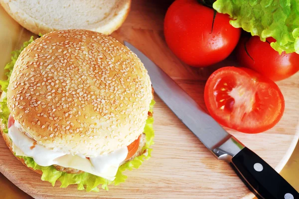 stock image Fresh and tasty hamburger with cheese and vegetables lies on plate