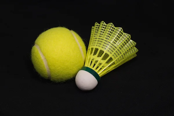 Gelber Tennisball und Federball isoliert auf schwarz — Stockfoto