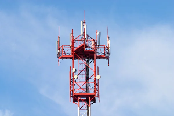 Röda och vita cellular torn med antenner på blå himmel — Stockfoto