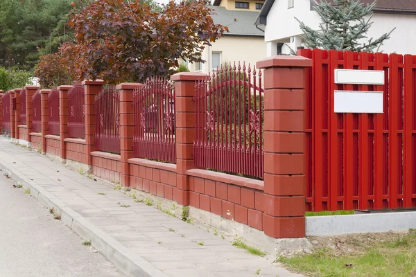 La cerca roja se encuentra en la calle rural —  Fotos de Stock