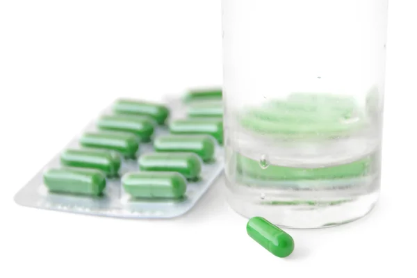 Zelené pilulky a sklo — Stock fotografie