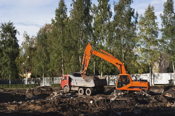 stock image Dump truck is being loaded with excavator