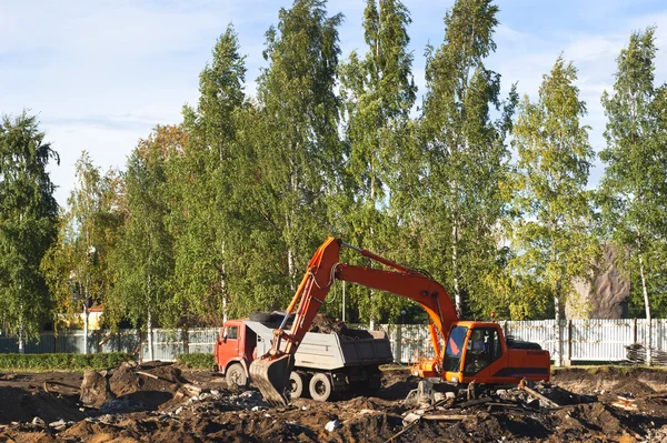 stock image Dump truck is being loaded with excavator