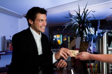 Man at the bar paying with gold credit card clipart