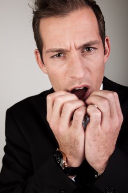 Stressed Businessman Biting His Nails And Scratching His Head clipart