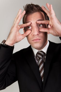 Businessman trying to stay awake by propping his eyes clipart