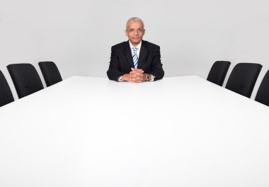 Businessman sitting alone in the empty boardroom