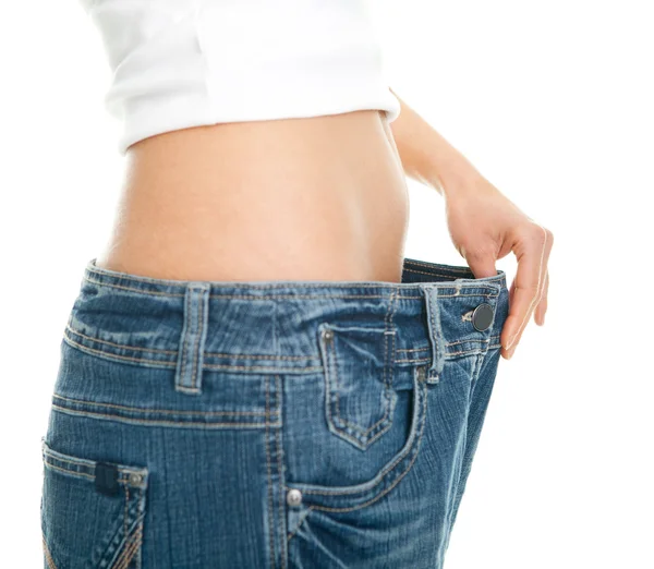Slim woman pulling oversized jeans — Stock Photo, Image