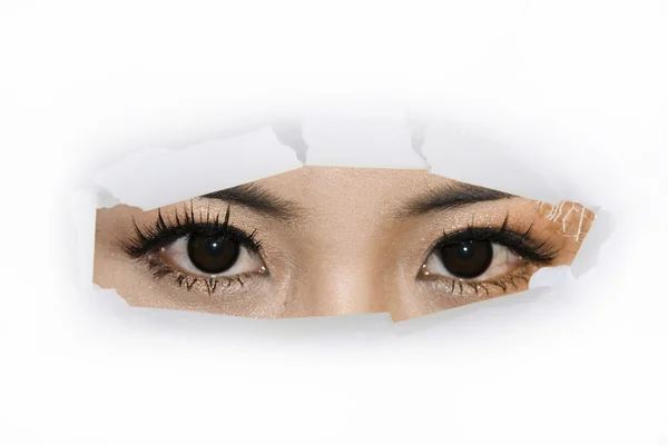 stock image A woman eyes looking through cut paper hole