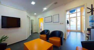 Waiting room. Interior of a dental clinic in orange and white and simple furniture. clipart